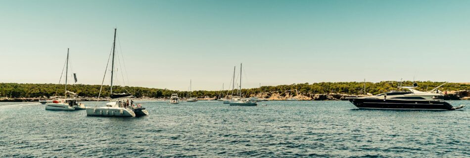 Picturesque scene of sailboats and yachts on Ibiza's clear waters under a bright summer sky.