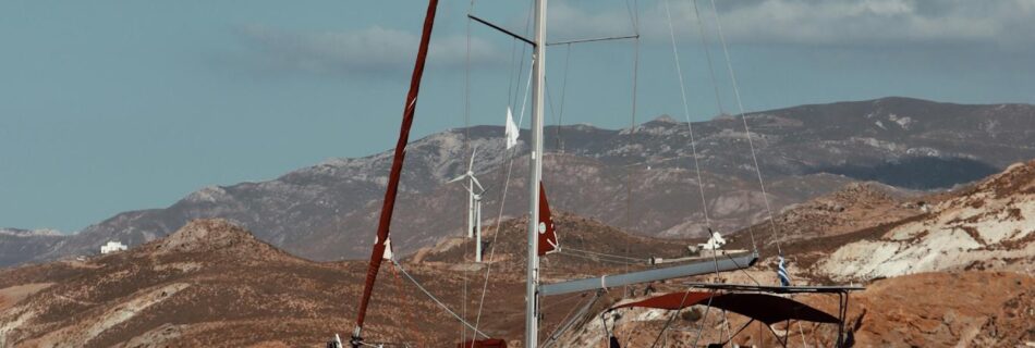 Serene view of a sailing yacht anchored off the rocky coast of Naxos in the Aegean Sea, Greece.